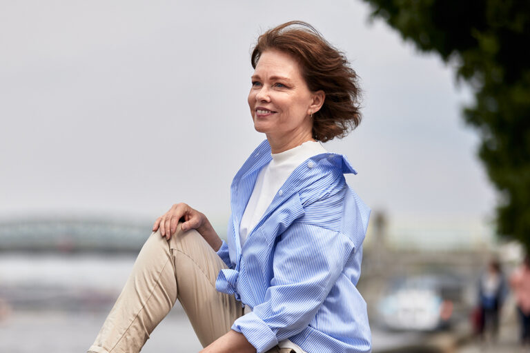 Mature woman sitting outdoors, representing facelift recovery and healing in Palm Beach Gardens.