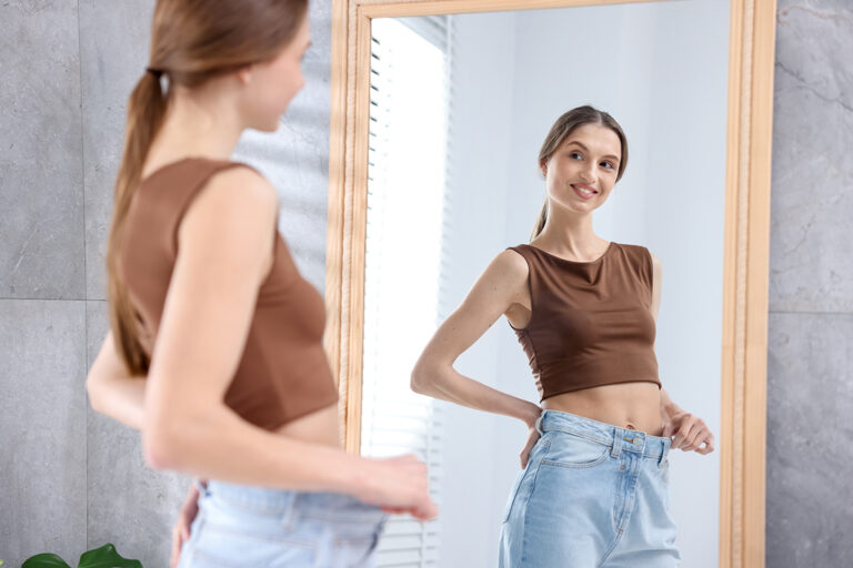 Woman checking her waist after major weight loss, representing tummy tuck and liposuction options after gastric sleeve surgery.