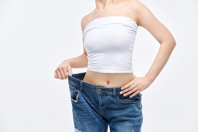Woman showing loose jeans, representing liposuction options and body contouring in Palm Beach Gardens.