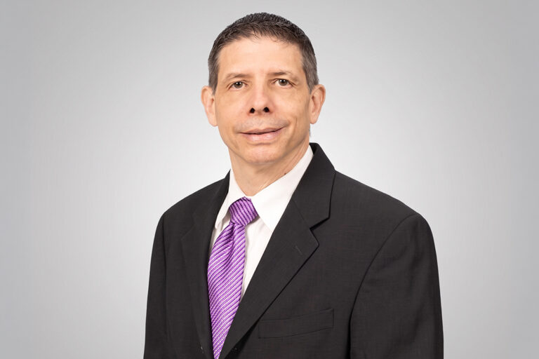 Professional portrait of a plastic surgeon in a black suit and purple tie for Atlantic Coast Aesthetics.