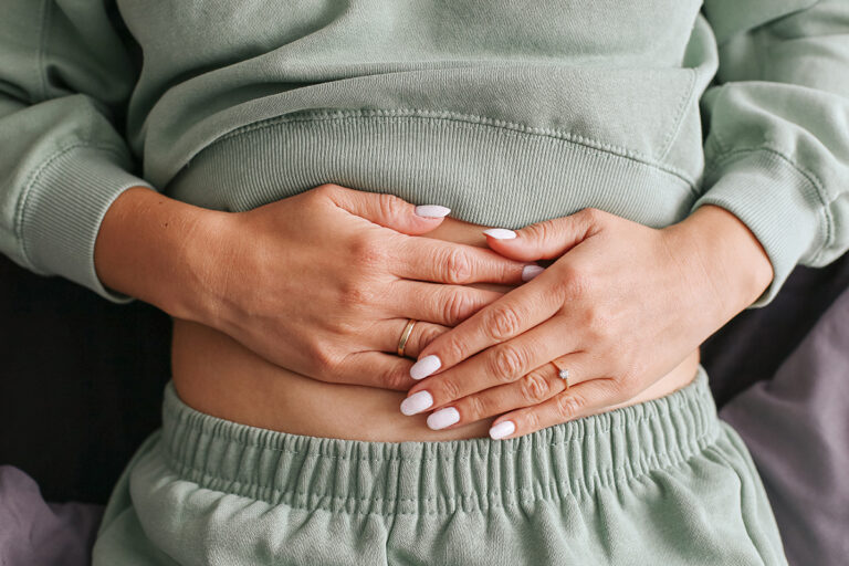 Woman holding her abdomen, representing tummy tuck muscle tightening in West Palm Beach.