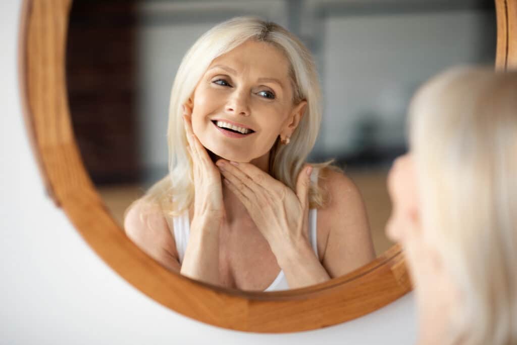 Woman looking in the mirror before nonsurgical neck tightening in Palm Beach Gardens