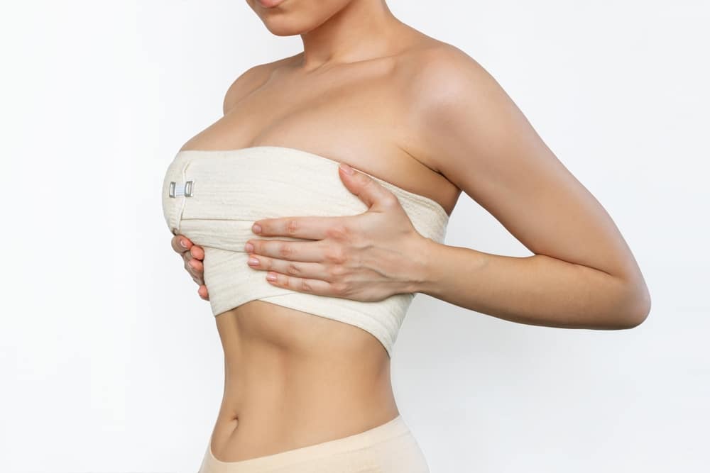 Woman wearing a post-surgical breast wrap representing breast reconstruction after cancer treatment in Palm Beach Gardens.