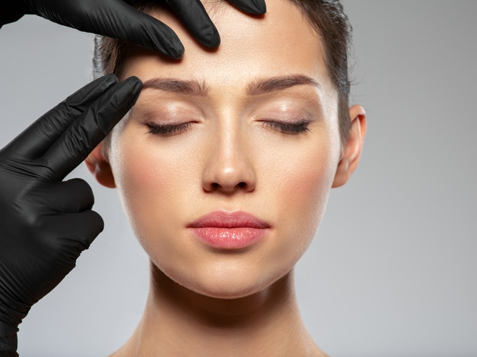 Woman receiving brow assessment representing browlift surgery and forehead rejuvenation in Palm Beach Gardens.
