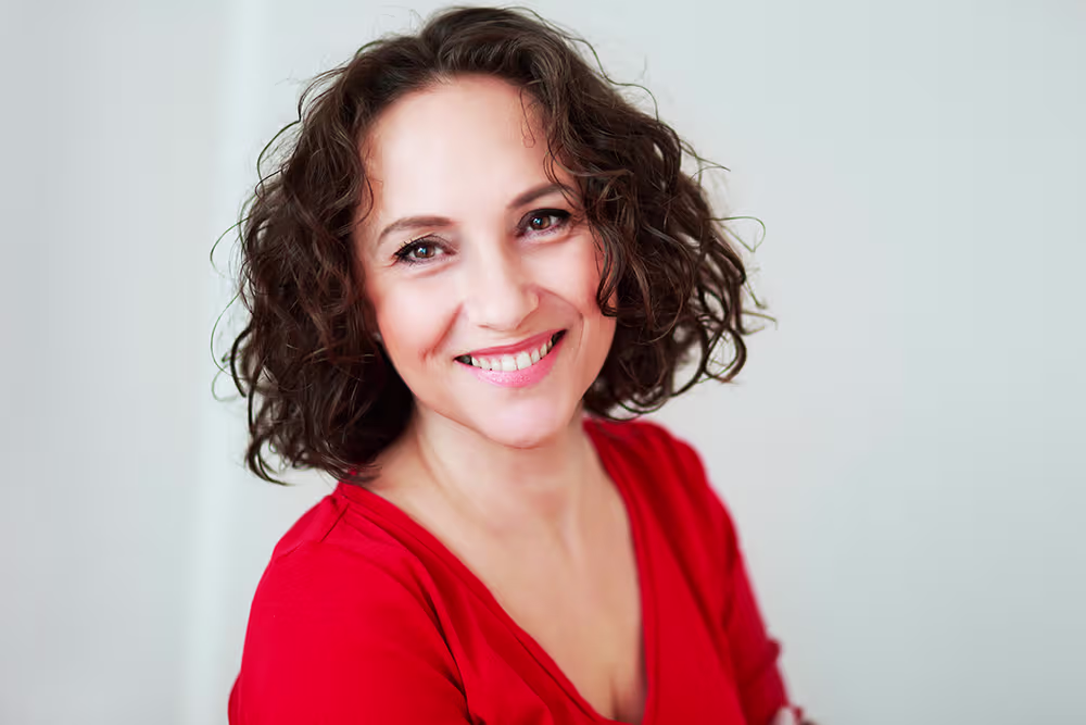 Smiling woman with hair framing her ears, illustrating how facelift incisions can be concealed around the ears.