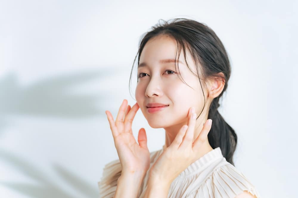 Woman touching her cheek representing natural-looking facial volume enhancement with fat transfer in Palm Beach Gardens.