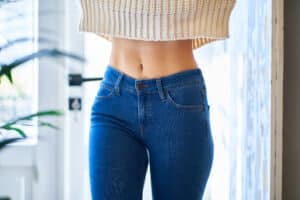 Slim waist in jeans representing liposuction fat removal and body contouring in Palm Beach Gardens.