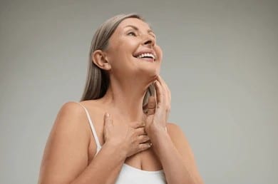 Smiling mature woman touching her neck, representing personalized neck rejuvenation in Palm Beach Gardens.